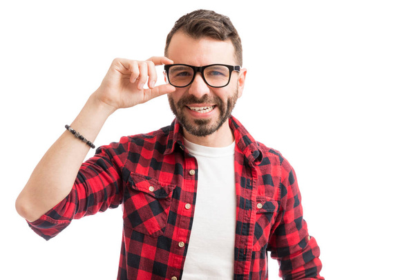 Komea mies säätää silmälasit ja hymyilee tavallisella taustalla
 - Valokuva, kuva