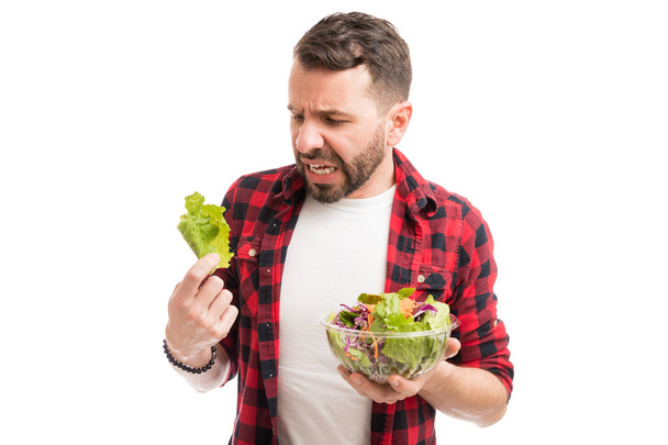 Muž, který se znechuceně dívá na salát s touhou vyhnout se dietě - Fotografie, Obrázek