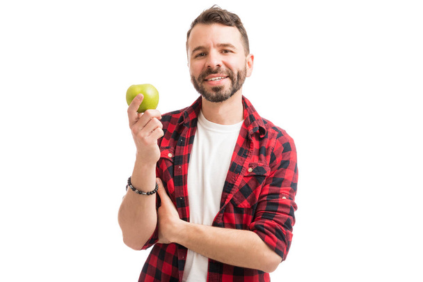 Homem bonito em camisa xadrez segurando uma maçã e sorrindo no branco
 - Foto, Imagem