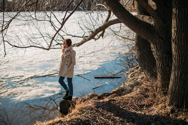 La fille se tient au bord du lac gelé au printemps
. - Photo, image