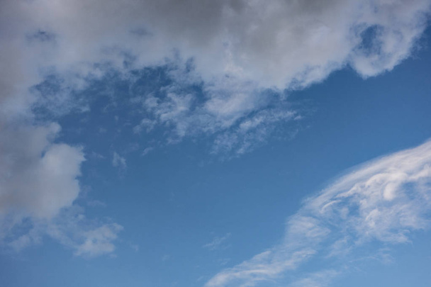 blauwe hemel met witte onregelmatige wolken achtergrond - Foto, afbeelding