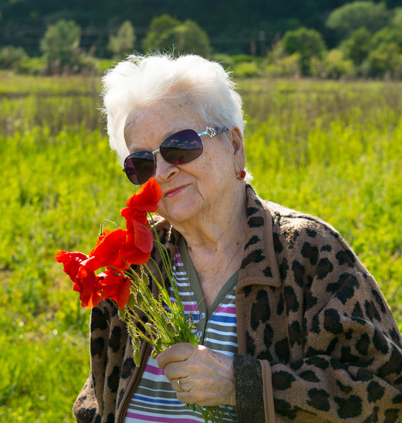 ηλικιωμένη γυναίκα σε γυαλιά ηλίου με μάτσο παπαρούνες - Φωτογραφία, εικόνα