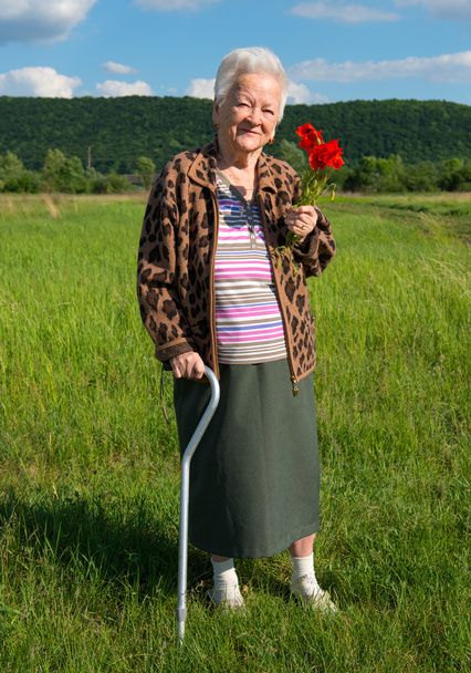 Old woman with bunch of poppy flowers - Photo, Image