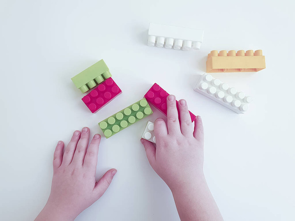 mani bambino giocare con blocchi di plastica su sfondo bianco
 - Foto, immagini