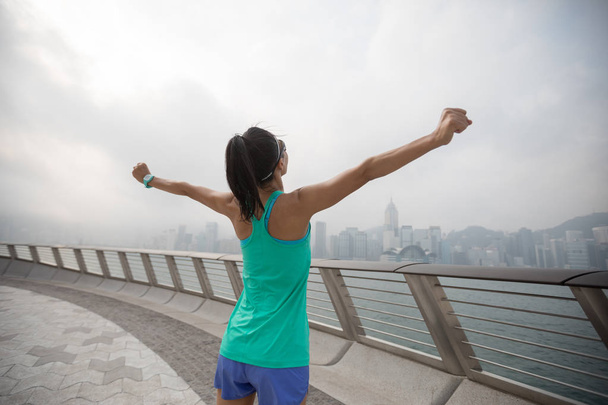 Zdrowy styl życia Kobieta biegacz z wyciągniętymi ramionami na mgliste miasto rano - Zdjęcie, obraz