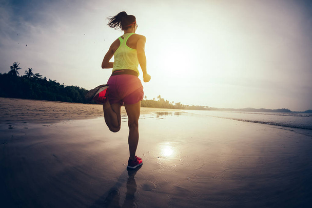 Fitness woman runner running on sunrise beach  - Foto, Bild