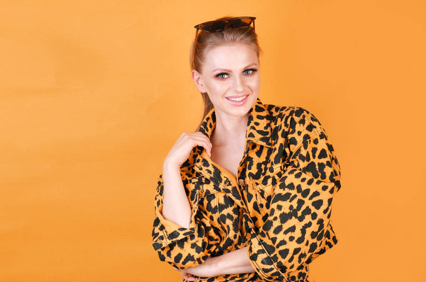 Charmante blonde meisje in Casual Animal gedrukte kleding in een kleurrijke achtergrond. - Foto, afbeelding