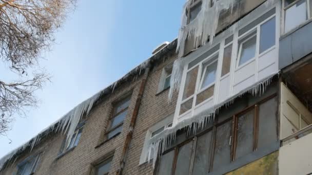 Old abandoned house and its balcony with a huge amount of melting icicles in winter. - Filmati, video