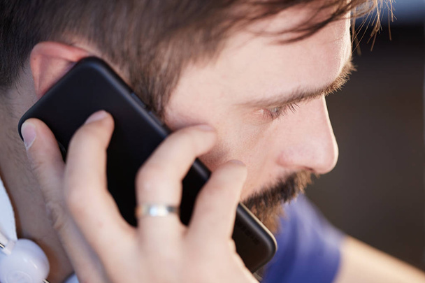 Handsome bearded man using mobile smartphone at office. Blurred background. - Foto, afbeelding