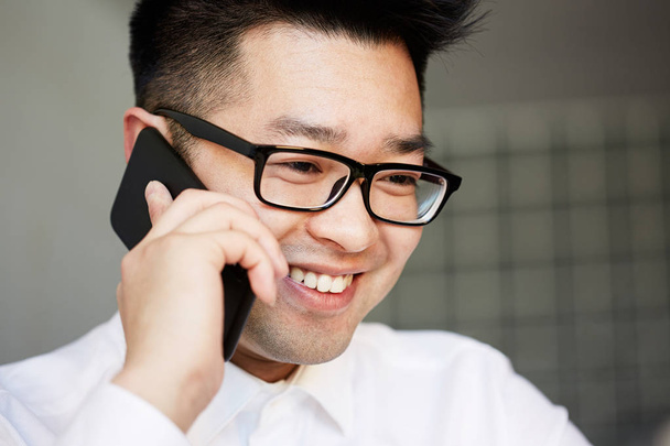 Asian businessman talking on the mobile phone in the office - 写真・画像