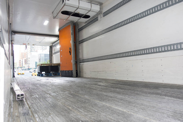 wewnątrz pustego ładunku przedsiębiorcy ciężarówki z otwartym pomarańczowym drzwi zaparkowane na ulicy Nowego Jorku z żółtymi kabin i innych ruchu - Zdjęcie, obraz
