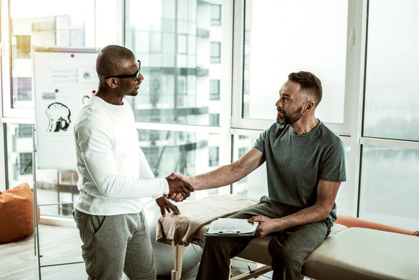 Cheerful male person shaking hands with his doctor - Foto, Imagen