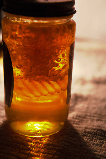 fresh amber local honey in a jar with wax honey comb cells insid - Valokuva, kuva