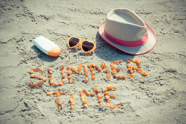 Czas letni napis, Okulary przeciwsłoneczne, krem przeciwsłoneczny i słomkowy kapelusz na piasku na plaży - Zdjęcie, obraz
