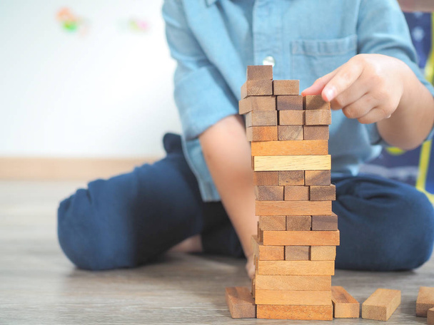 Small kid playing with wooden blocks on the floor - 写真・画像