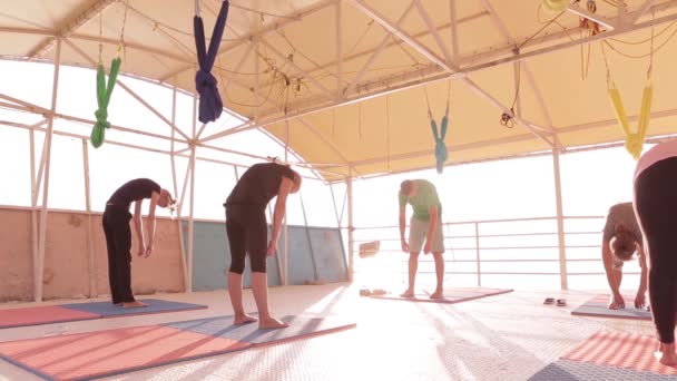 Jooga luokka aikuisten naisten ja yhden miehen käytännössä jooga ja tehdä hengitysharjoituksia ohjaaja rannalla auringonnousun
. - Materiaali, video