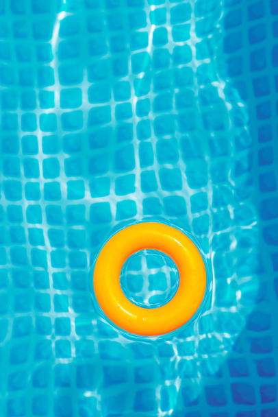 anillo inflable amarillo flotando en la piscina en el día soleado, vista superior
 - Foto, Imagen