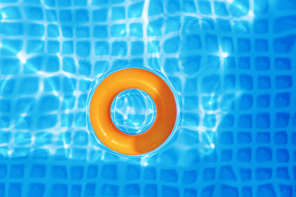 orange Inflatable ring floating in swimming pool on sunny day, top view - Photo, Image