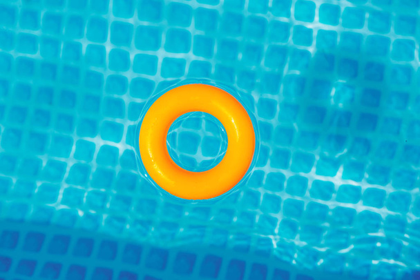 κίτρινο φουσκωτό δαχτυλίδι που επιπλέει στην πισίνα την ηλιόλουστη μέρα, κορυφή θέα - Φωτογραφία, εικόνα