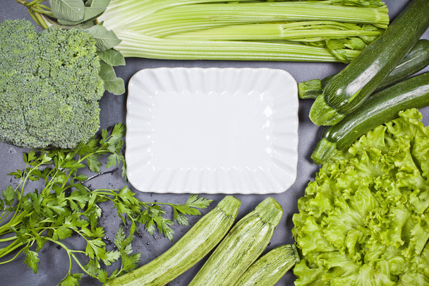 Variety of green vegetables and white ceramic plate.  - Fotoğraf, Görsel