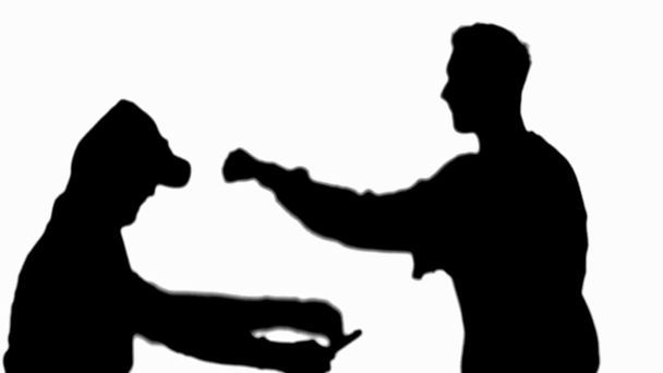 silhouette of man fighting with criminal holding knife, winning and showing yes gesture isolated on white - Footage, Video