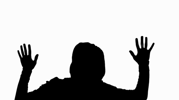 silhouette of man in hood holding palms up and going down isolated on white - Materiaali, video