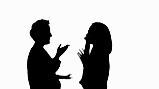 Side view of two silhouettes of women kissing during meeting, laughing and gesturing isolated on white - Footage, Video