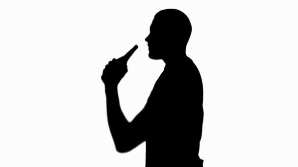 Boční pohled na siluetu člověka, který pomalu pije pivo izolované na bílém - Záběry, video