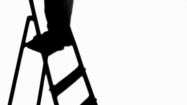 silueta člověka, který se dívá nahoru a stoupá po žebříku izolovanému na bílém - Záběry, video