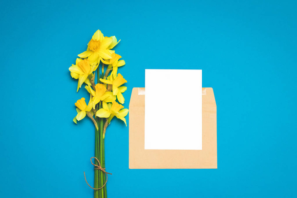 Fresh bouquet of flowers of narcissus on a bright blue background. Greeting card layout for positive ideas. Empty place for inspirational, emotional, sentimental text or quotation. - Photo, Image