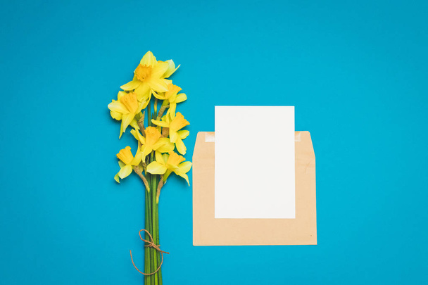 Fris boeket bloemen van narcissen op een heldere blauwe achtergrond. Wenskaart lay-out voor positieve ideeën. Lege plaats voor inspirerende, emotionele, sentimentele tekst of citaat. - Foto, afbeelding