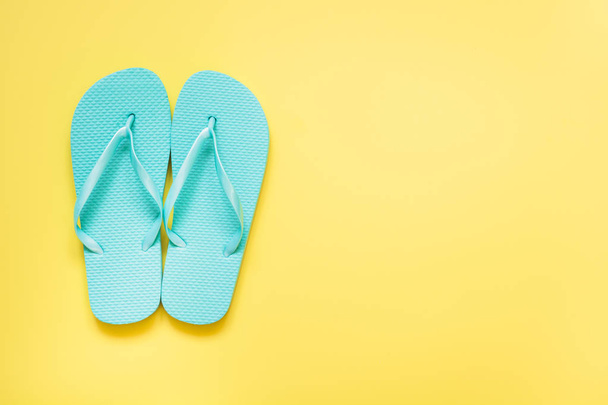 blauer Strand-Flip-Flop auf knallgelbem Hintergrund. Tropischer Sommerurlaub. - Foto, Bild