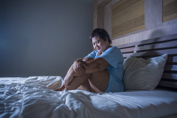 young sad and depressed fat and chubby Asian girl feeling upset and desperate crying on bed at home victim of bullying and discrimination for her plus size and overweight - Photo, Image