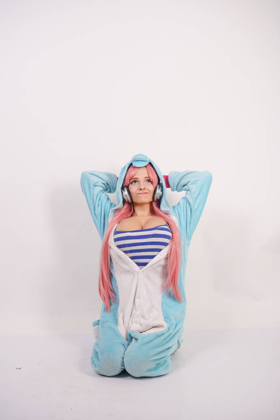 aranyos fiatal lány rózsaszín hosszú haj kék Egyszarvú pizsamában és puha vicces papucs, fehér háttér-a stúdió - Fotó, kép
