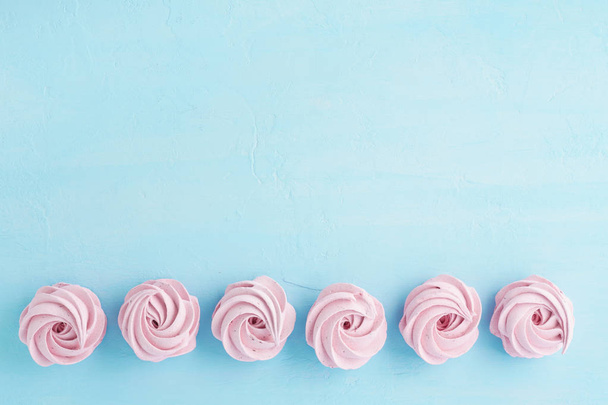 Pink marshmallow of zephyr op lichte blauwe achtergrond. Plat leggen. - Foto, afbeelding