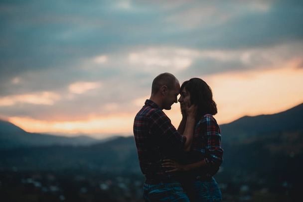 couple enjoying beautiful sunset sitting together on the mountain with great view - Photo, Image