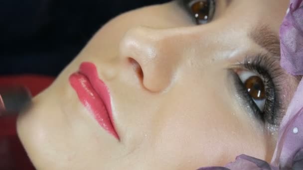 Αναμείξιμες επισημάνετε με επαγγελματική βούρτσα εφαρμόζεται στο πρόσωπο του μοντέλου close up. Νεαρό κορίτσι μοντέλο με όμορφα καστανά μάτια στο στούντιο. Επαγγελματικό make-up από υψηλής μόδας μακιγιάζ καλλιτέχνης - Πλάνα, βίντεο