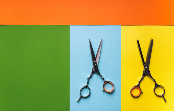 Scissors of hairdresser on the background of pastel paper in the form of multi-colored stripes. Minimalist pop art concept. - Valokuva, kuva