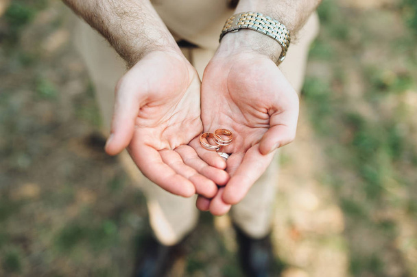 Close up of two wedding rings on groom's palms. - Valokuva, kuva