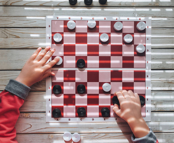 The child plays checkers. Children's hands on a checkerboard. Play board games. - Foto, Imagem