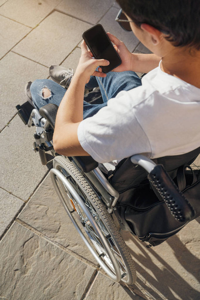 Cep telefonu kullanarak tekerlekli sandalyede genç adam portresi - Fotoğraf, Görsel