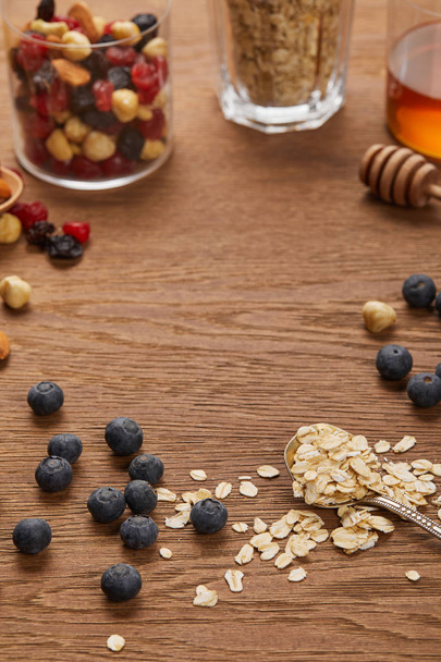 selective focus of oat flakes, nuts and dried berries on wooden table with copy space - Photo, Image