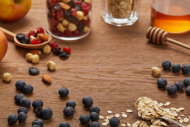 selective focus of oat flakes, nuts, honey and berries on wooden table with copy space - 写真・画像