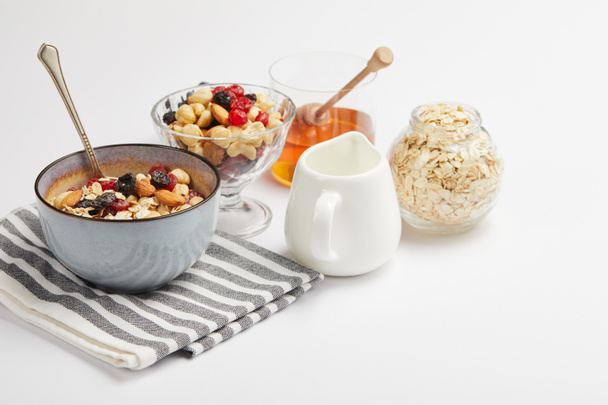 bowl on striped napkin with oat flakes, nuts and berries on white table with copy space - Photo, Image