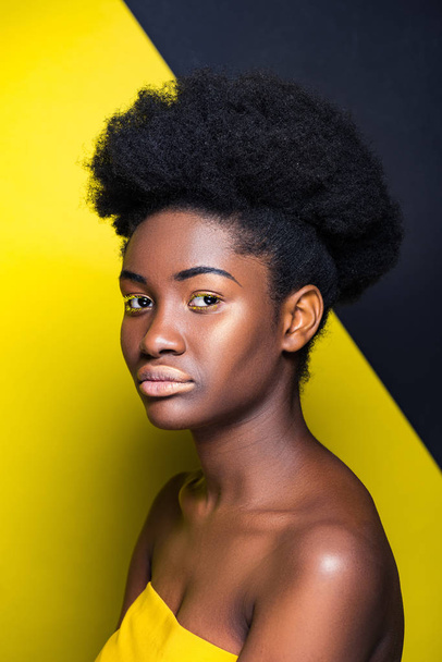 Attractive african american girl looking at camera on black and yellow - Фото, зображення