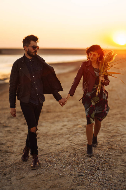 Enjoying time together.  Stylish and loving couple enjoying each other by the sea. The couple is young and in love. The concept of youth, love and lifestyle. Beautiful sunset on a summer day. - Fotó, kép
