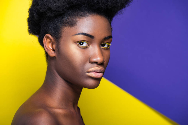 Serious african american woman looking at camera on yellow and purple - Foto, imagen