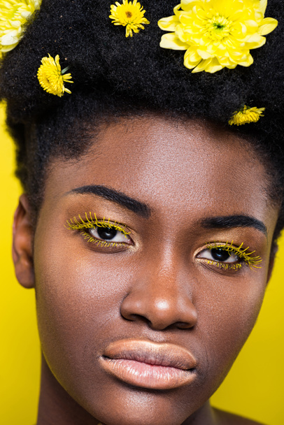 Portrét africké americké ženy s květinami ve vlasech izolovaných na žluté - Fotografie, Obrázek