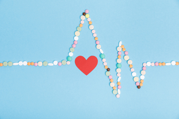 Flat lay with colorful pills and paper heart on blue - Fotoğraf, Görsel