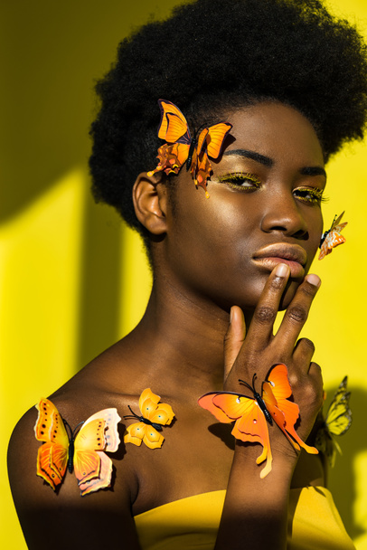 Pensive pretty african american woman with butterflies on yellow - Zdjęcie, obraz